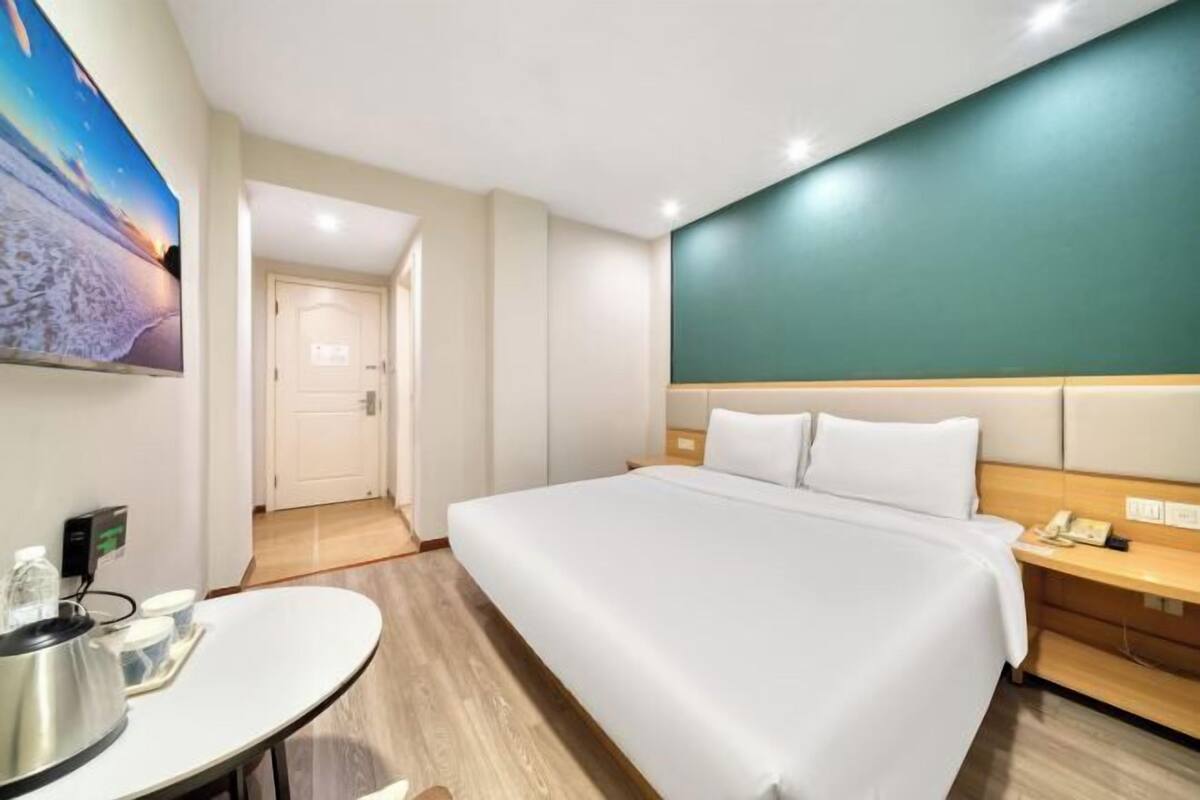 A hotel room with a bed, bedside table, and a wall-mounted TV.