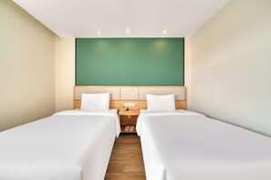 A hotel room with two single beds, a wooden nightstand with a phone, and a green accent wall. - Home Inn (Shanghai Qingpu Chengzhong North Road Shiji Lianhua Plaza) (Shanghai)