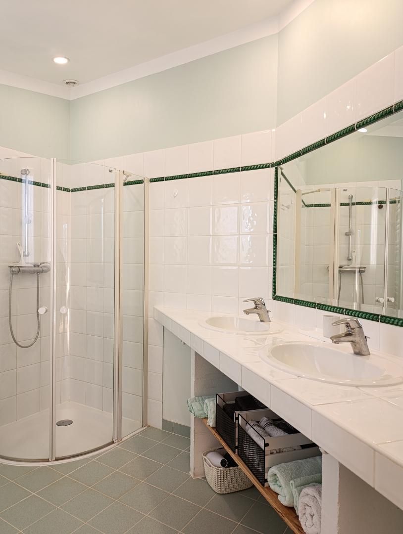 A bathroom with two sinks, a shower, and a mirror.