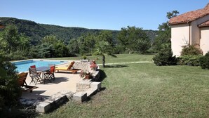 Un patio trasero con piscina, mobiliario exterior y un sendero de piedra que lleva a una casa.