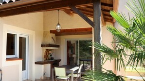 Un porche cubierto con una mesa y sillas, un lámpara colgante y vistas al exterior.