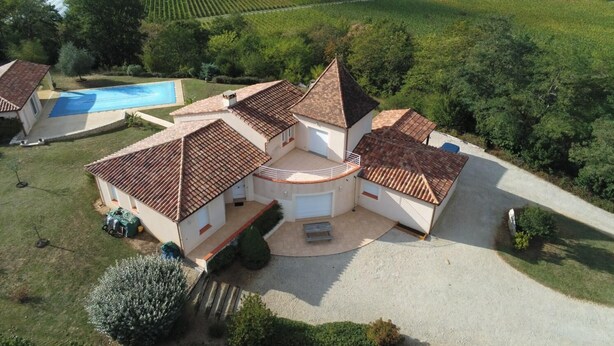 Una villa con piscina, cancha de tenis y un viñedo al fondo.