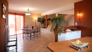 Un amplio espacio habitable con una mesa de comedor, sillas, una zona de cocina y una escalera que sube a un nivel superior.
