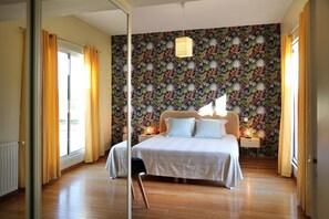 Une chambre à coucher avec un lit, une table de chevet, une lampe suspendue et une fenêtre avec des rideaux.