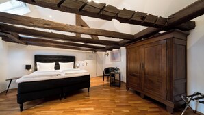 Ein Schlafzimmer mit Holzbalkendecke, einem Bett, einem Schrank und einem kleinen Tisch.