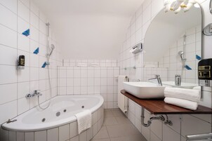 Un baño moderno con una bañera independiente, un lavamanos y un espejo grande.