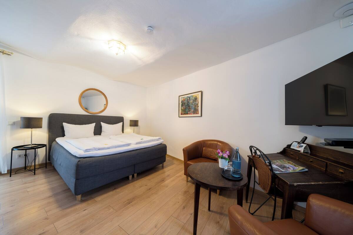 Une chambre d’hôtel moderne équipée d’un lit, d’un bureau, d’une chaise, d’une lampe et d’un téléviseur.