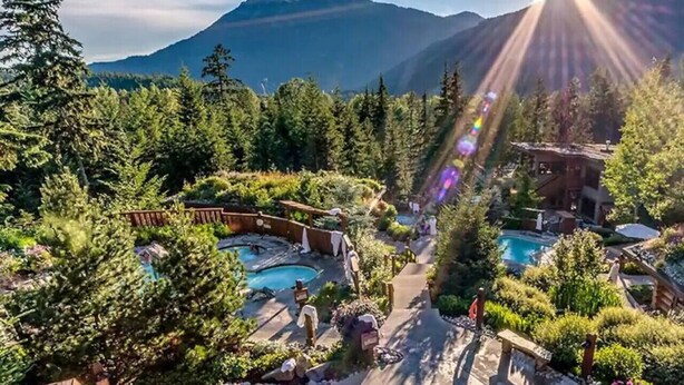 Un complexe hôtelier doté de plusieurs piscines, entouré d’une végétation luxuriante et avec des montagnes en toile de fond.
