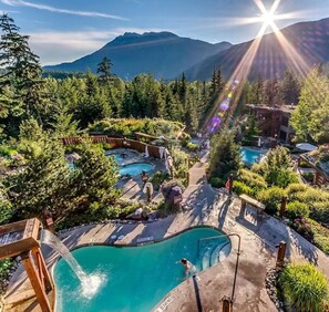 Un complexe hôtelier doté de plusieurs piscines, entouré d’une végétation luxuriante et avec des montagnes en toile de fond.