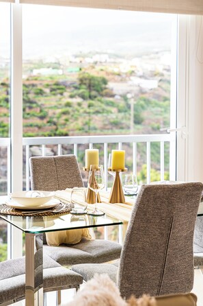 A dining area with a glass table, chairs, and candles.