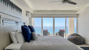 Ein Schlafzimmer mit Bett, Kissen, Deckenventilator und Meerblick.