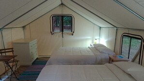 Alojamiento con carpa que incluye dos camas, una mesita, una silla y un armario.
