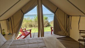A tented accommodation with a bed, a table, and chairs. - Safari Tent Glamping,S2-CedarPt, East Hampton, NY (East Hampton)