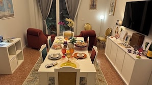 Un coin repas agrémenté d’un lustre, une table à manger dressée avec différents plats, et une vue sur l’extérieur par une fenêtre.