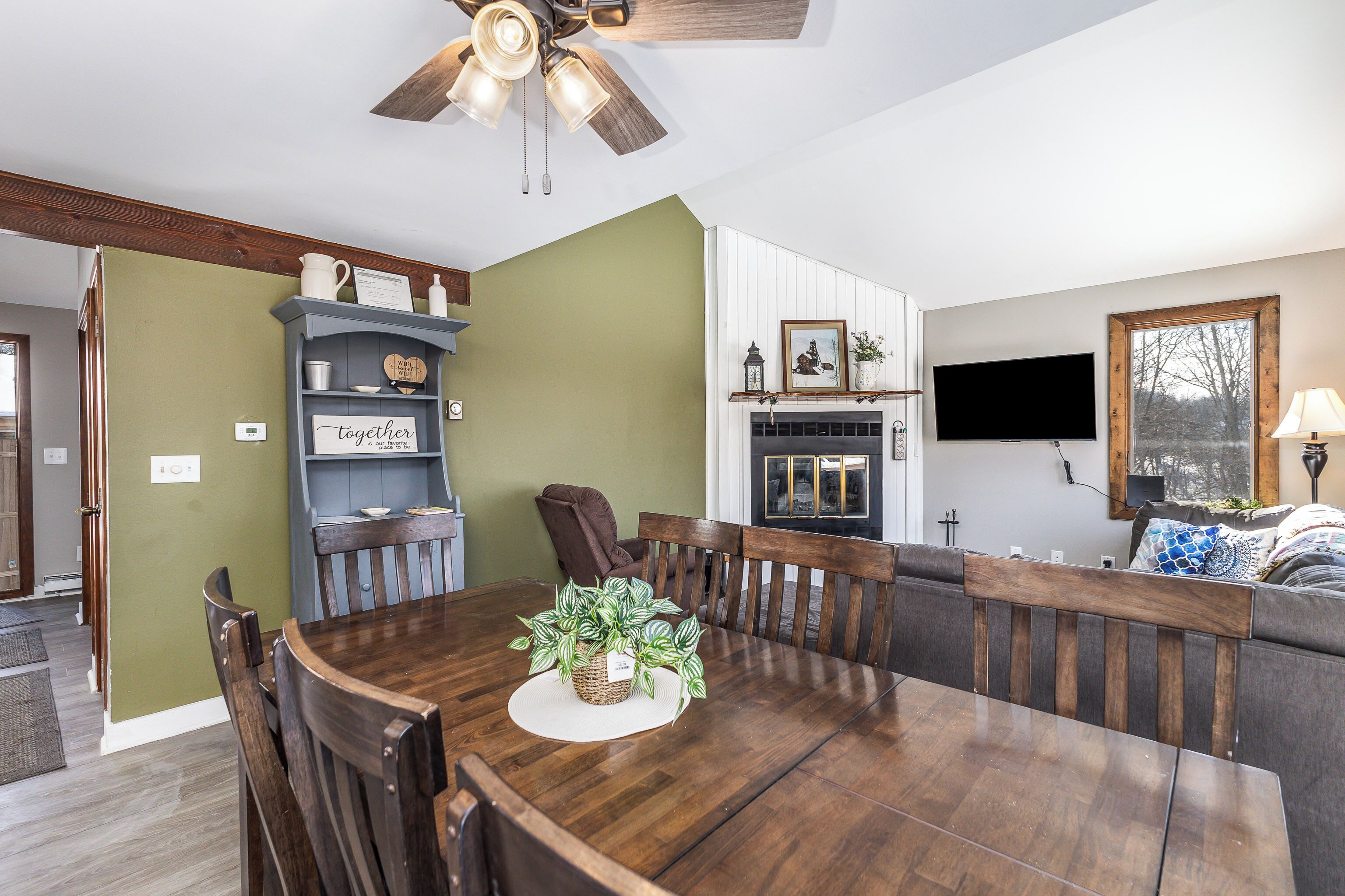 A dining area with a wooden table, chairs, and a ceiling fan.
