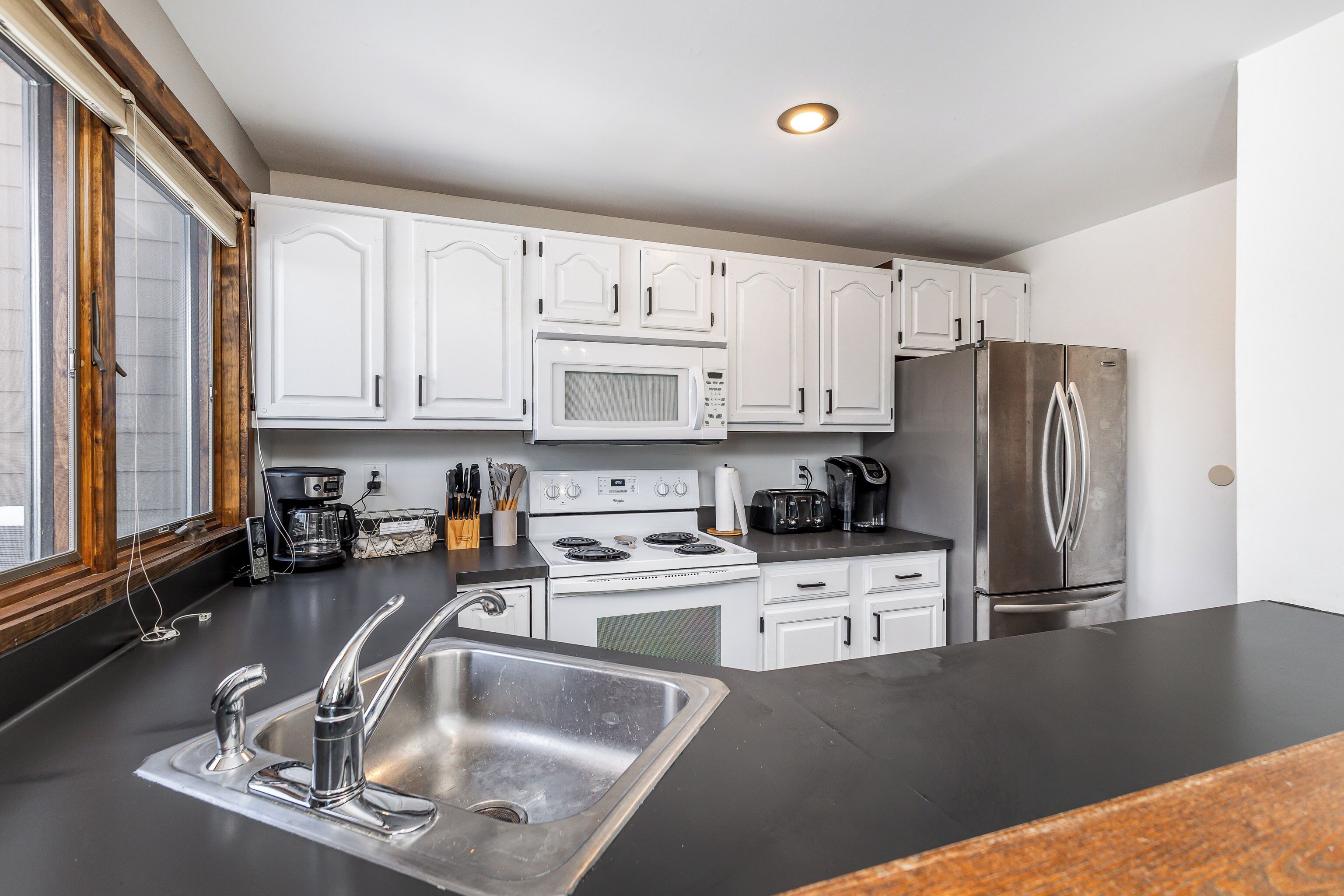 A modern kitchen with white cabinets, stainless steel appliances, and a black countertop.