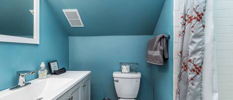 Un baño con lavamanos blanco, inodoro y cortina de ducha con motivos florales.