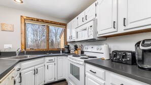 A modern kitchen with white cabinets, a built-in microwave, a stove, and a toaster. - Cozy Retreat at Farmstead (Galena)