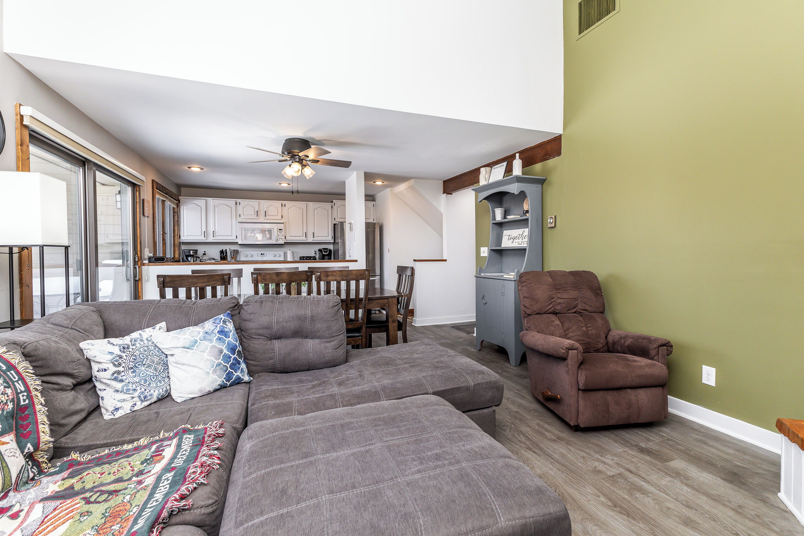 A living room with a sectional sofa, a recliner, and a dining area with a table and chairs.