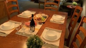 A dining area with a wooden table set for six, surrounded by chairs. A chandelier hangs above the table, and there is a potted plant on the table. - O'Tremblant-Nature with Fireplace/Plein air avec foyer (Mont-Tremblant)