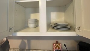 A kitchen cabinet with shelves, one shelf holding stacked bowls and another with stacked plates.