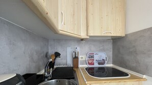 Eine kleine Küche mit Holzausstattung, einer Spüle, einer Kaffeemaschine und einem Toaster.
