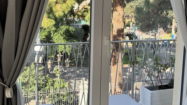 Un balcon donnant sur des arbres et muni d’une balustrade.