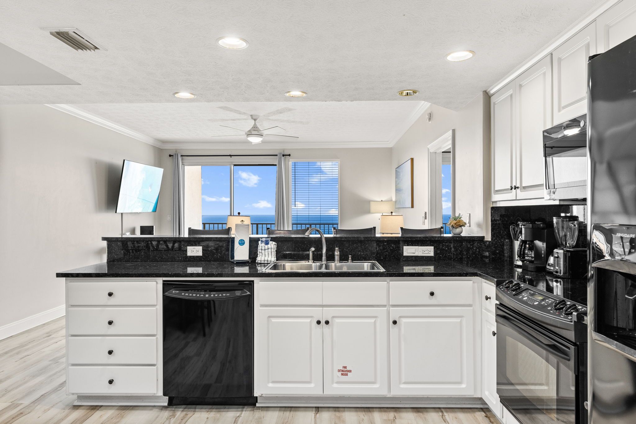 Una cucina moderna con una grande isola, elettrodomestici integrati e vista all'esterno.