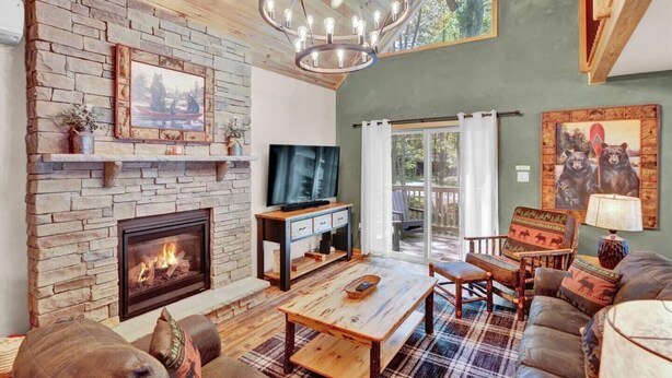 A cozy living room with a stone fireplace, a television, and a plaid rug. - Emerald Bliss, MiniGolf Bowling Playset Beach Horseshoe Cornhole (Towamensing Trails)