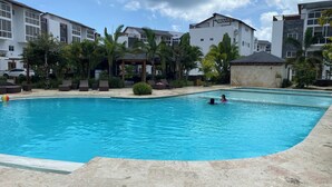 A swimming pool with lounge chairs and a gazebo, surrounded by buildings and palm trees. - EXPECTACULAR APARTAMENT DE 2 HABITACIONES (Las Terrenas)