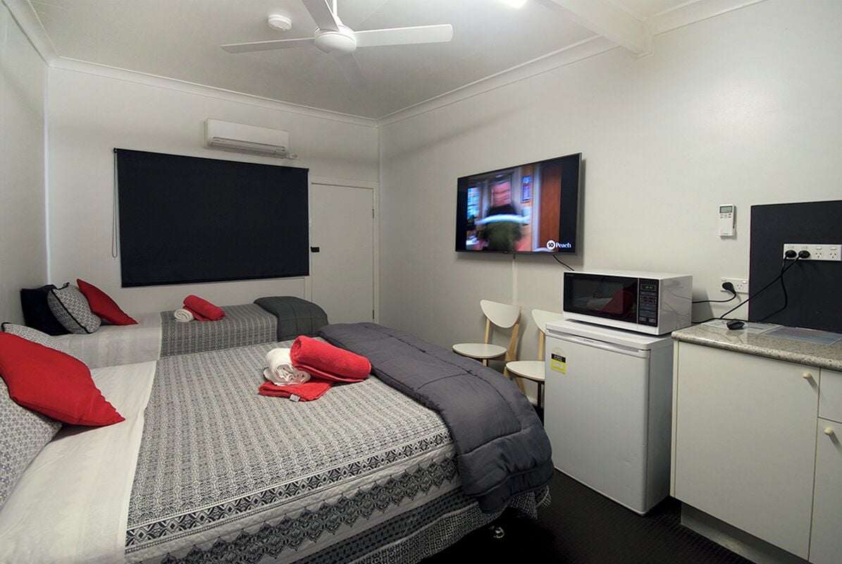 Habitación de hotel con dos camas, televisión, microondas y escritorio con silla.