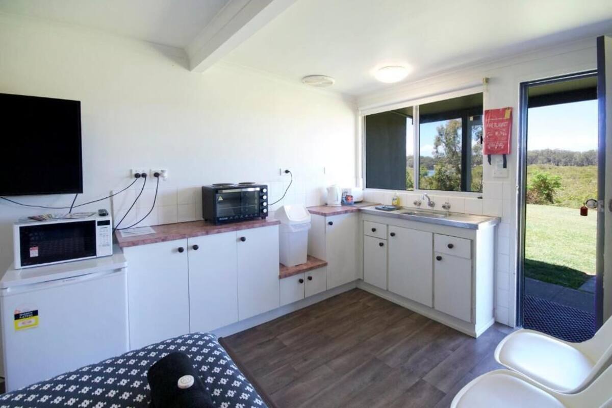 A compact kitchen with white cabinets, a microwave, a toaster, and a sink.