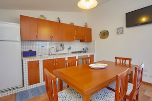 Een koelkast, een oven, kookgerei, borden en bestek