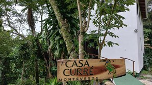 Un letrero de madera con la inscripción 'CASA CURRE MONTEVERDE' e ilustración de un loro.