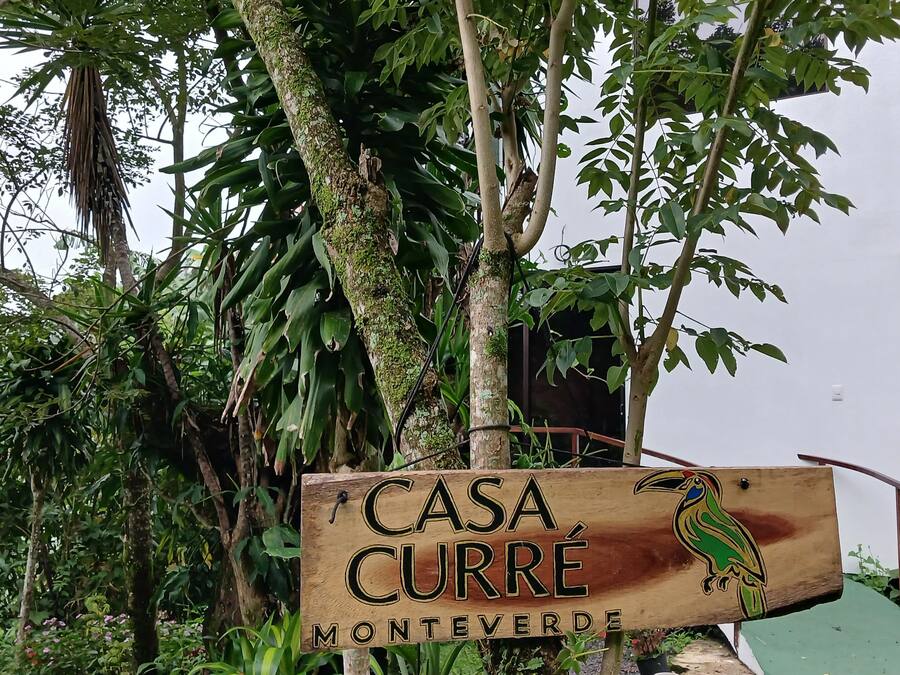 A wooden sign with 'CASA CURRE MONTEVERDE' and a parrot illustration.