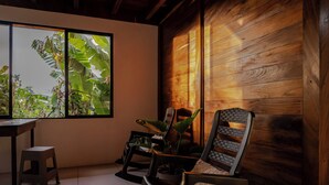Una habitación con pared de madera, ventana con vistas a plantas, un escritorio y dos sillas.