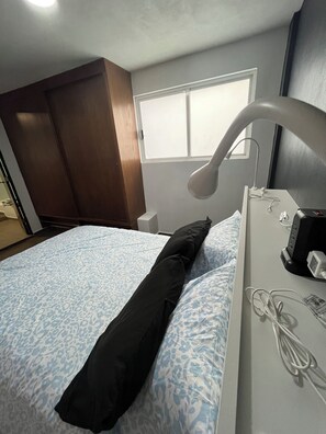 A hotel room with a bed, a desk with a lamp, and a window. - Departamento Rompecabezas SúperAnfitrión (Mexico City)