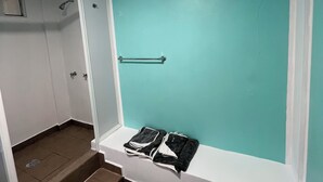 Un baño con pared verde azulado, un perchero y una zona de ducha.