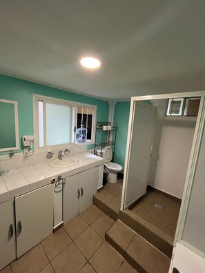 A bathroom with a white sink, mirror, and toilet, a shower area, and a window. - Departamento Rompecabezas SúperAnfitrión (Mexico City)