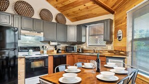 Una cucina moderna con mobili grigi, soffitto in legno e un tavolo da pranzo per quattro persone.