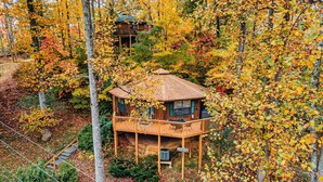 Una baita di legno con un balcone, immersa nel foliage autunnale.