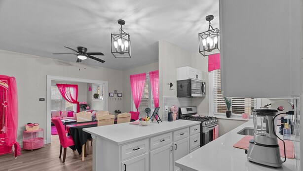A modern kitchen with white cabinetry, a central island, and a ceiling fan.