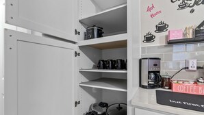 A kitchen with white cabinets, a coffee station, and a wall with motivational quotes.