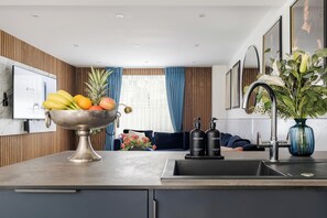 A modern kitchen with a fruit bowl, a sink, and a vase with flowers.