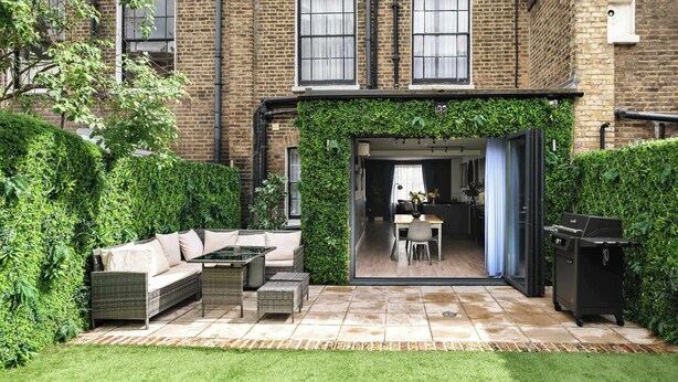 A brick building with a patio area featuring a sofa, a table, and a grill. - Stunning 4BR 3BA in the   ♥️ of London ❄️ Air Con. 🌿 Private Garden | Sleeps 10 (Greater London)