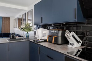 A modern kitchen with dark cabinets, a coffee machine, and a knife block. - Stunning 4BR 3BA in the ♥️ of London ❄️ Air Con. 🌿 Private Garden | Sleeps 10 (Greater London)
