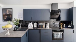 A modern kitchen with dark cabinetry, a built-in oven, and a coffee maker. - Stunning 4BR 3BA in the ♥️ of London ❄️ Air Con. 🌿 Private Garden | Sleeps 10 (Greater London)