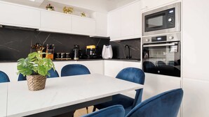 Eine moderne Küche mit weißen Schränken, einer Marmorarbeitsplatte, einer Kaffeemaschine und einer Mikrowelle.