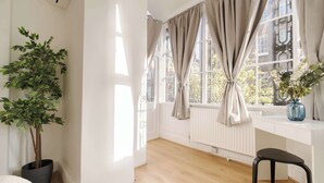 A bright room with a large window, a potted plant, a radiator, and a chair. - Elegant 2BR in the ♥️ of Marylebone ❄️ Air Conditioning ☀️ Terrace (Greater London)