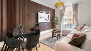 A modern living room with a dining area, a mounted TV, a chandelier, and a view of buildings through a window. - Elegant 2BR in the ♥️ of Marylebone ❄️ Air Conditioning ☀️ Terrace (Greater London)